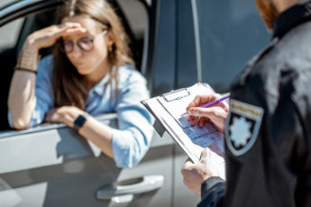 A women in the black car getting a ticket from a cop