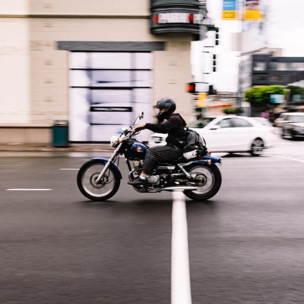 man rides a motorcycle down a street