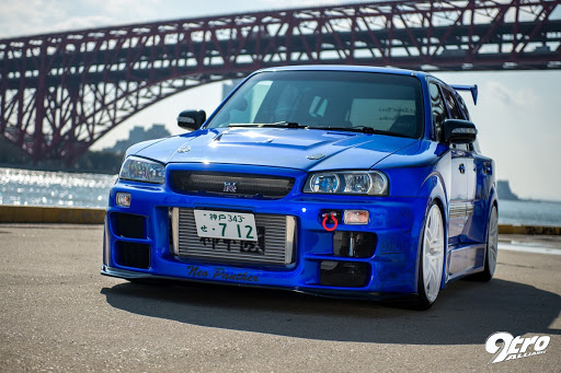 A blue car parked outside with a view of a huge bridge