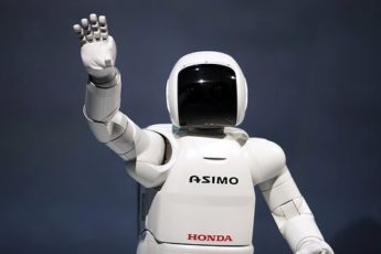 The white Honda Asimo robot is waving to the crowd