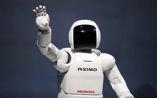 The white Honda Asimo robot is waving to the crowd