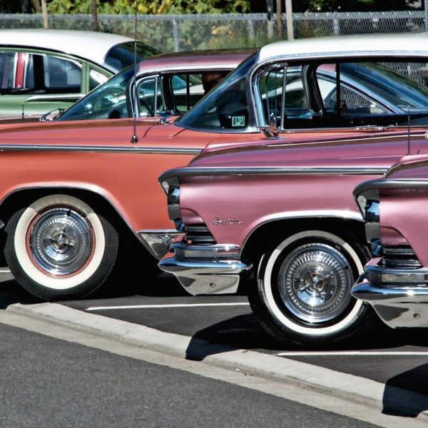 Display of vintage cars, colors pink, orange, green.