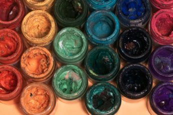 A bunch of bottle filled with various colors of paint that are organized neatly in rows, with each row dedicated to paints of the same hue.