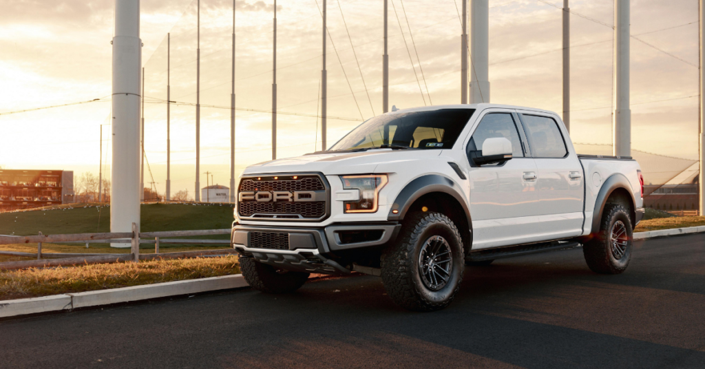 A white Ford F-Series truck parked by some poles.