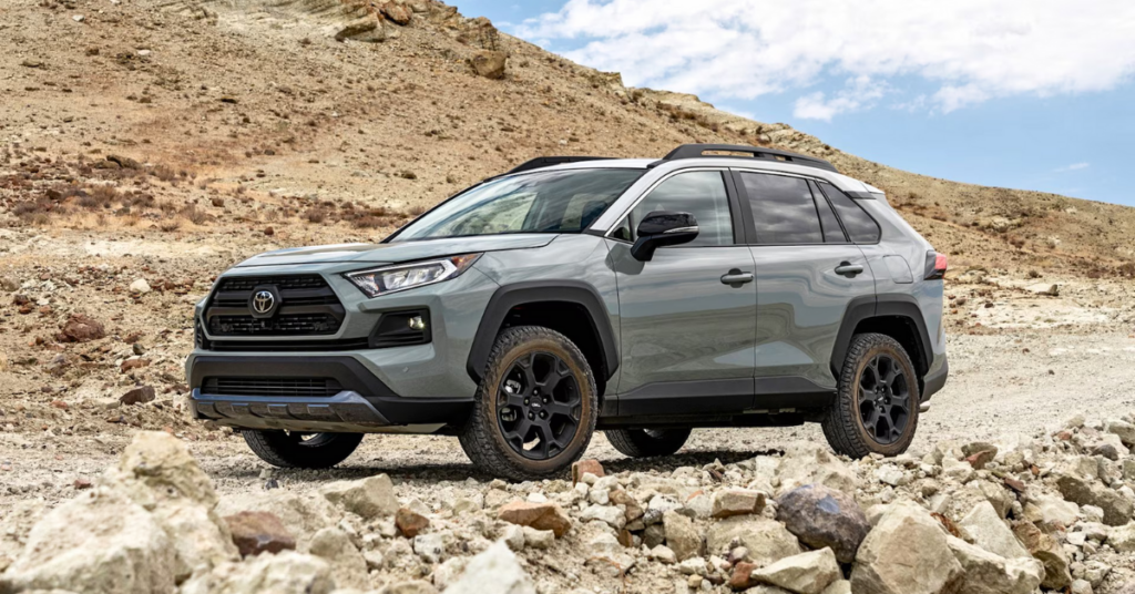 A gray Toyota RAV4 parked by a rocky hill.