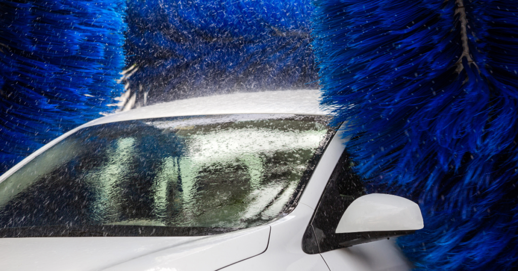 A white car goes through the brushes at a car wash.