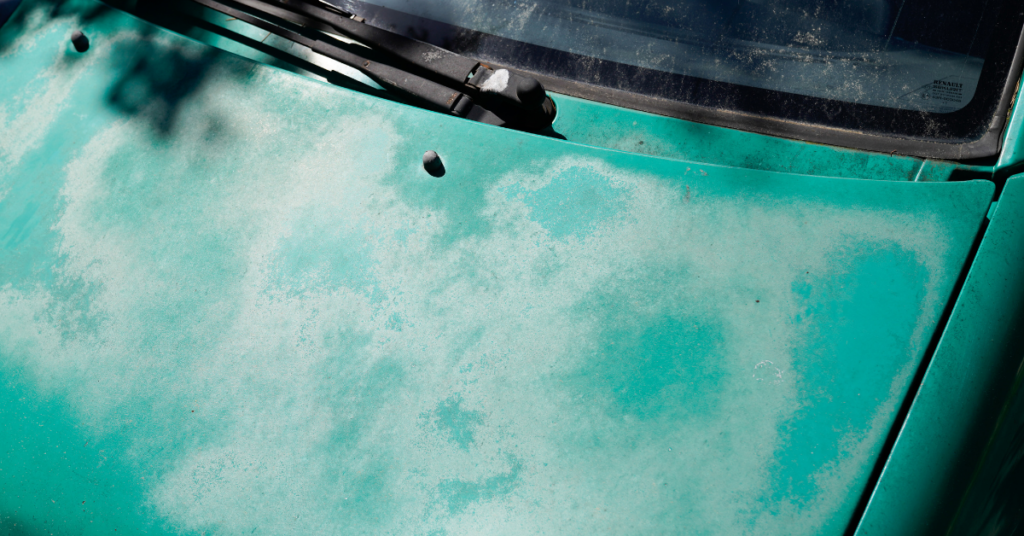 A teal car that shows signs of fading.