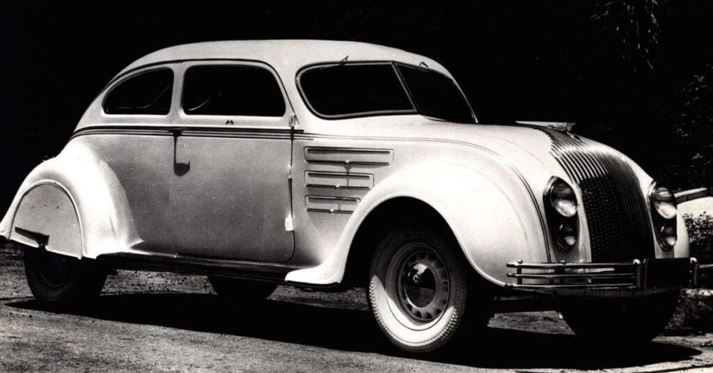 A black and white photo of a 1934 Chrysler Airflow on the road.