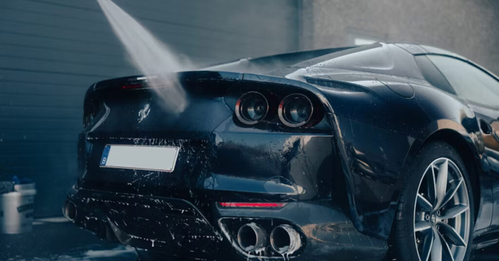 A spray of water washes the back of a black sports car.