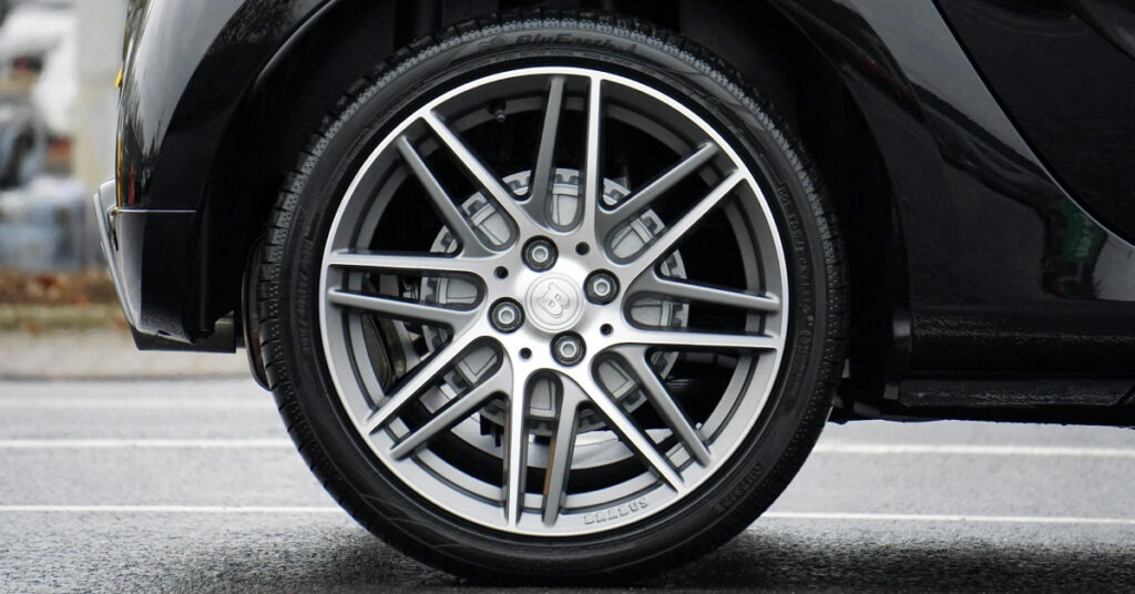 A wheel with fancy rims on a black car.
